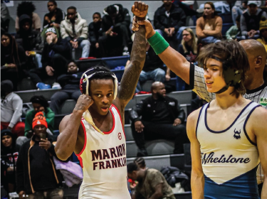 Wrestler holding arms up as they are crowned winner of the match